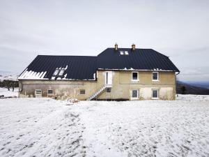una casa con techo negro en la nieve en Urtica apartmány en Nová Ves v Horách