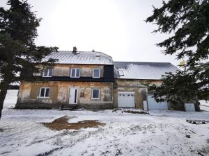 una vieja casa de piedra en la nieve con árboles en Urtica apartmány en Nová Ves v Horách