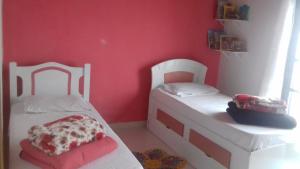 2 camas blancas en una habitación con paredes rojas en marias, en Campos do Jordão