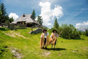 two people dressed in costumes standing in a field with kites at Chalet Tisa Velika Planina in Stahovica