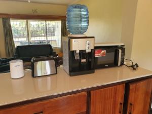 a kitchen counter with a coffee maker and a microwave at Thayo Place in Nyeri
