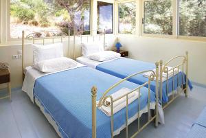 two beds in a bedroom with two windows at Anemus in Sivota