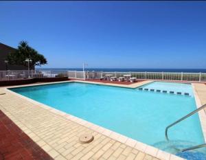 a large swimming pool with the ocean in the background at Eden Dunes - Shelly Beach in Margate