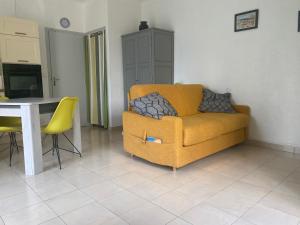 ein Wohnzimmer mit einem gelben Sofa und einem Tisch in der Unterkunft Joli studio avec parking à 2 min à pied de la plage in Argelès-sur-Mer
