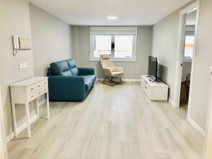 Una sala de estar con un sofá azul y un televisor. en Apartamento Muralla, en Lugo