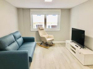 Una sala de estar con un sofá, una silla y un televisor. en Apartamento Muralla, en Lugo