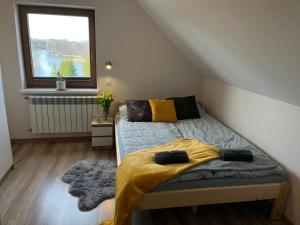 1 dormitorio con 1 cama con manta amarilla y ventana en Domek z kominkiem nad jeziorem z jacuzzi ogrodowym, en Sumowo