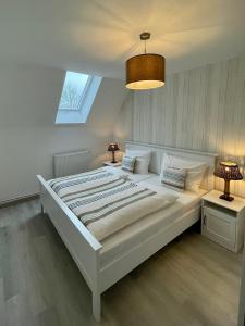 ein weißes Schlafzimmer mit einem großen weißen Bett und einem Fenster in der Unterkunft Inselwohnung Nordstrand in Nordstrand