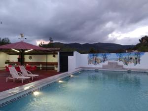 a large swimming pool with chairs and an umbrella at Villa Frasquita in Priego de Córdoba
