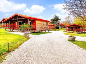 a log cabin with a red roof on a gravel road at LES CHALETS DE SANCERRE in Thauvenay