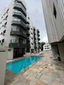 a swimming pool in front of a tall building at Apartamento no Guarujá Enseada a beira mar, ótima localidade e com ar condicionado in Guarujá