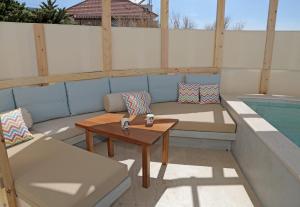 patio con divano, tavolo e piscina di Bella Mare Sitia a Sitia