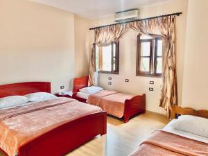 1 dormitorio con 2 camas y ventana en HOTEL RESTORANT VIKTORIA, en Gjirokastra