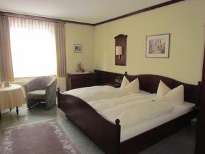 una camera con un grande letto e una sedia di Hotel Zum Erker a Trebur