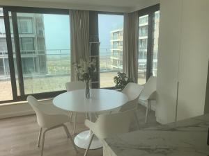 a white table and chairs in a room with a window at Sea View Penthouse in De Panne