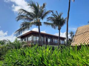 a house with palm trees in front of it at Beach Premium Praia do Forte in Praia do Forte