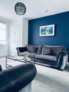 ダルケイスにあるDalkeith Five Bedroom Houseの青い壁のリビングルーム(ソファ2台付)