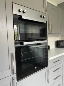 a black oven in a kitchen with white cabinets at Five Bedroom Five Bathroom House - Dalkeith in Dalkeith
