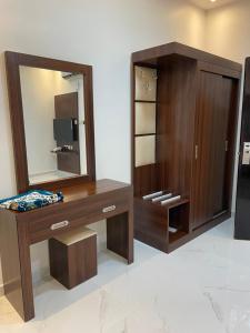 a dressing room with a mirror and a wooden cabinet at تربل وان للشقق المخدومة in Ruqaiqah