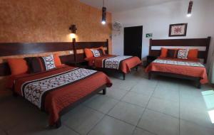 une chambre d'hôtel avec deux lits et un banc dans l'établissement Kali Huasteca Posada, à Ciudad Valles