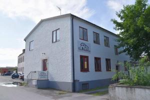 un edificio blanco con puertas rojas y ventanas en una calle en Elisabets Vandrarhem Hemse, en Hemse