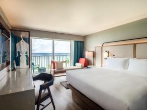 タモンにあるクラウンプラザリゾートグアムの大きなベッドとバルコニーが備わるホテルルームです。