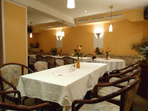 ein Esszimmer mit Tischen und Stühlen mit weißem Tischtuch in der Unterkunft Hotel-Restaurant Marcus in Malchin
