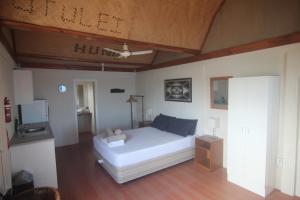 Schlafzimmer mit einem weißen Bett und einem TV in der Unterkunft Boathouse Apartments in Neiafu