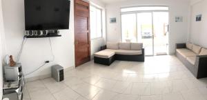 a living room with a couch and a tv at Bravo Surf Camp Punta Rocas in Punta Negra