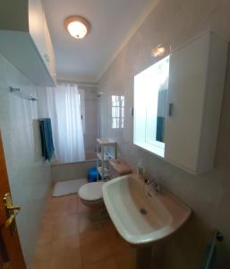een badkamer met een wastafel, een toilet en een spiegel bij Schöne Ferienwohnung auf Teneriffa in Los Silos