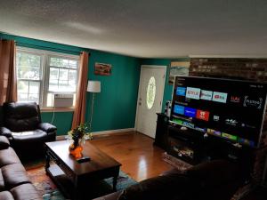 a living room with a couch and a large screen tv at Thompson House Cape Cod in South Yarmouth