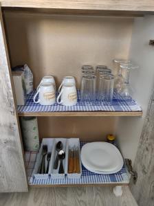 un estante con jarras y utensilios. en Aloha - Sobe sa kupatilom, en Golubac