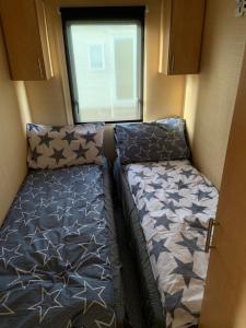 two beds in a small room with a window at L38 Caravan Mablethorpe With ramp and gated decking in Mablethorpe