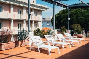 una fila di sedie bianche sedute su un patio di Arcangelo Roof Hotel a Rimini