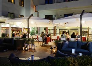 a restaurant with couches and people sitting at tables and umbrellas at Best Western Hotel Rome Airport in Fiumicino