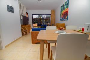 comedor y sala de estar con mesa y sillas en Duplex Meloneras with Free Wifi and private Garden en Meloneras