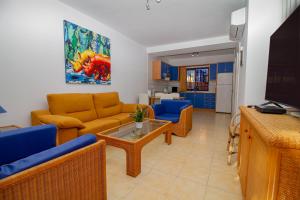 sala de estar con muebles amarillos y azules y TV en Duplex Meloneras with Free Wifi and private Garden en Meloneras