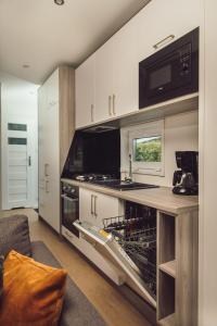 cocina con lavavajillas abierto y microondas en Tiny Cabin with Hottub I 4 p, en Rijssen