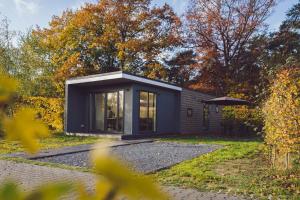 a black house in the middle of a garden at Tiny Cabin with Hottub I 4 p in Rijssen