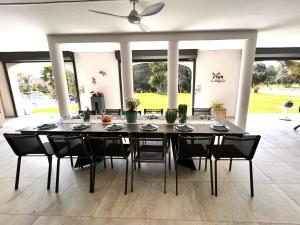 a dining room table with black chairs and a ceiling fan at Villa des Cabres in Lunel