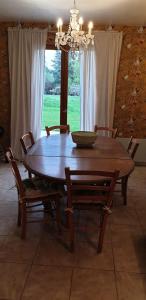 een houten tafel en stoelen in een kamer met een raam bij Maison entre relooking et modernité dans un cadre verdoyant pour amoureux de grands espaces in Nogent-sur-Vernisson