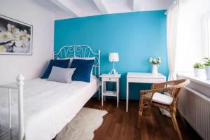sypialnia z niebieską ścianą, łóżkiem i krzesłem w obiekcie Urban Nest Apartments Szewska 21-19 w Krakowie