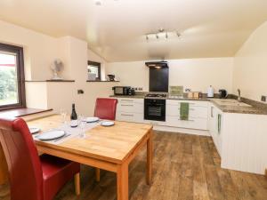 uma cozinha com uma mesa de madeira e cadeiras vermelhas em Millers Retreat em Bolsover