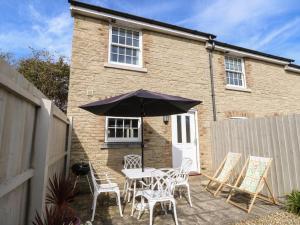 a patio with a table and chairs and an umbrella at 4 The Old Post Office Mews in Brading