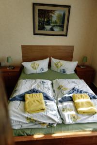 ein Bett mit weißer Bettwäsche und gelben Handtüchern darauf in der Unterkunft Pension Kristall in Elbingerode
