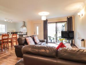 a living room with a brown leather couch and a kitchen at Pebbles Cottage in Contin