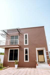 a brown house with a balcony on top at Baldwin Beauty House in Accra