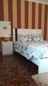a bedroom with a bed and a night stand with a lamp at O Cantinho do Sol (Estúdio Chocolate) in Lourinhã