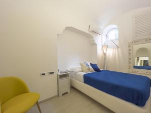 a bedroom with a blue bed and a green chair at Capri center holidays in Capri
