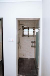 baño con ducha a ras de suelo y puerta en Baldwin Beauty House, en Accra